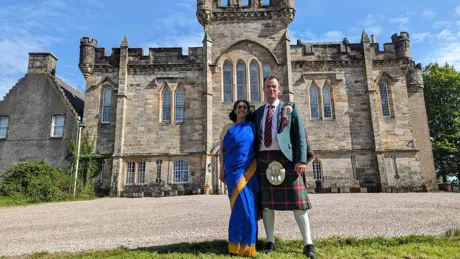 A Man And A Woman In Costumes Standing In Front Of Laird Simon Castle, Scotland