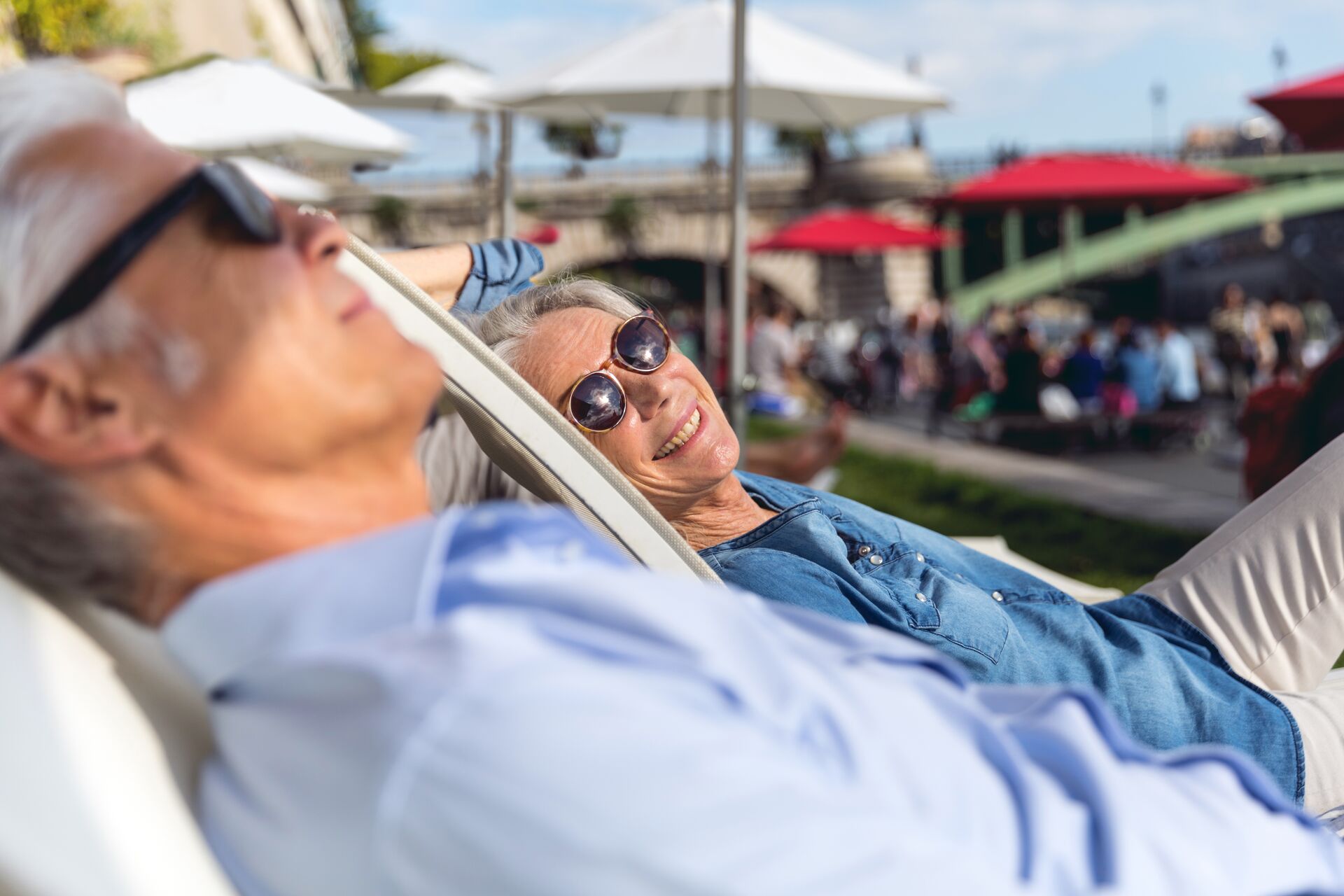 Older couple relaxing on deck chairs while exploring Paris, France on a sunny day