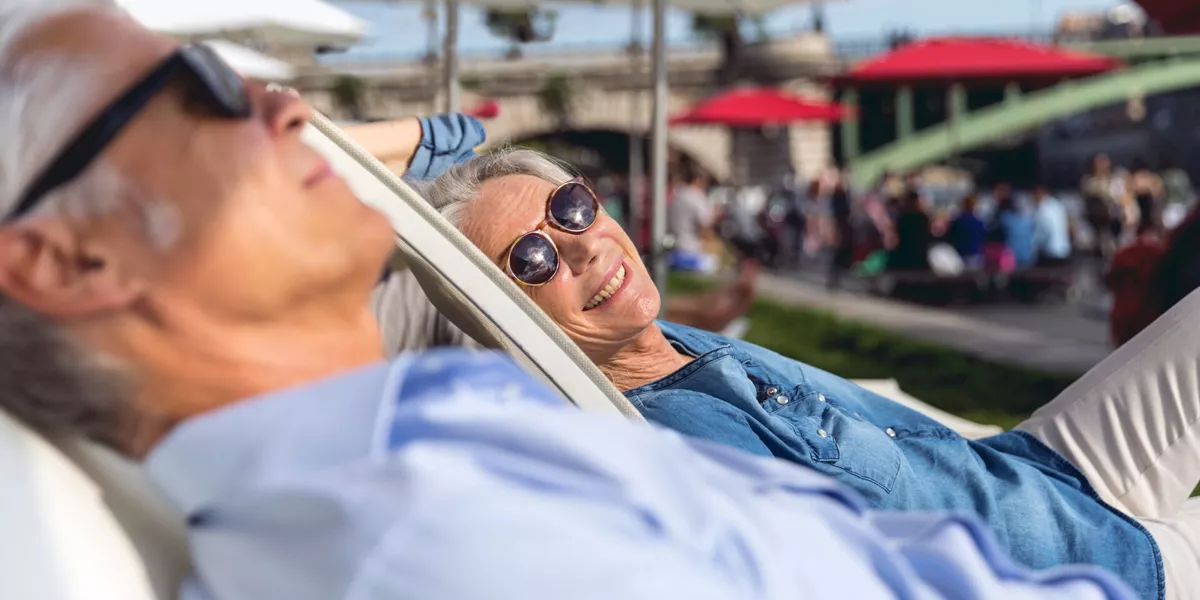 Older couple relaxing on deck chairs while exploring Paris, France on a sunny day