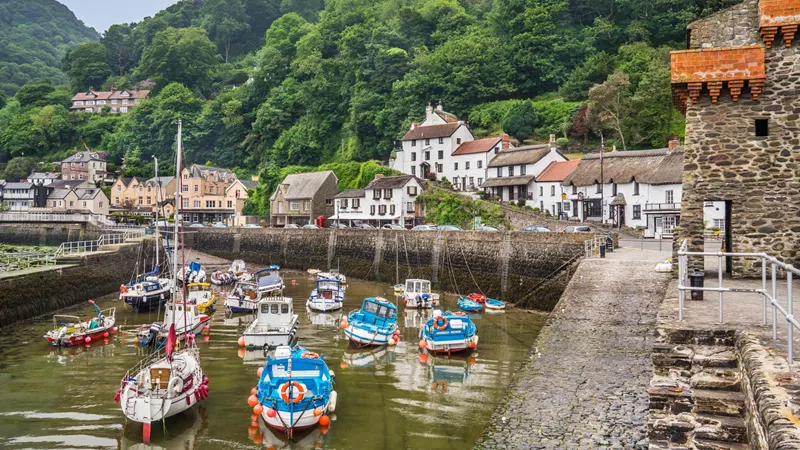 Lynmouth harbour with boats, cottages and green hills in Devon, England.