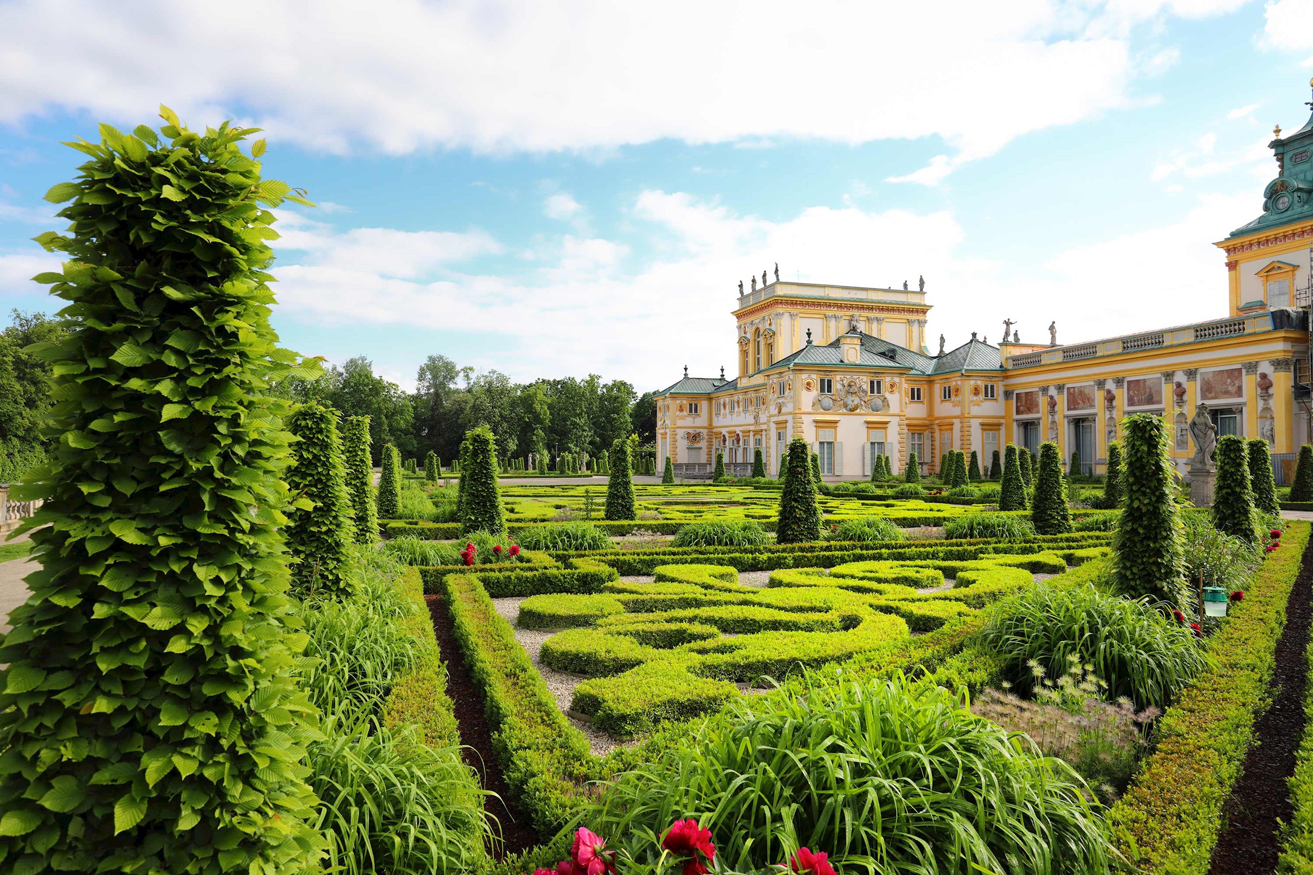 Formal garden with trimmed hedges and ornate palace in background in Warsaw, Poland