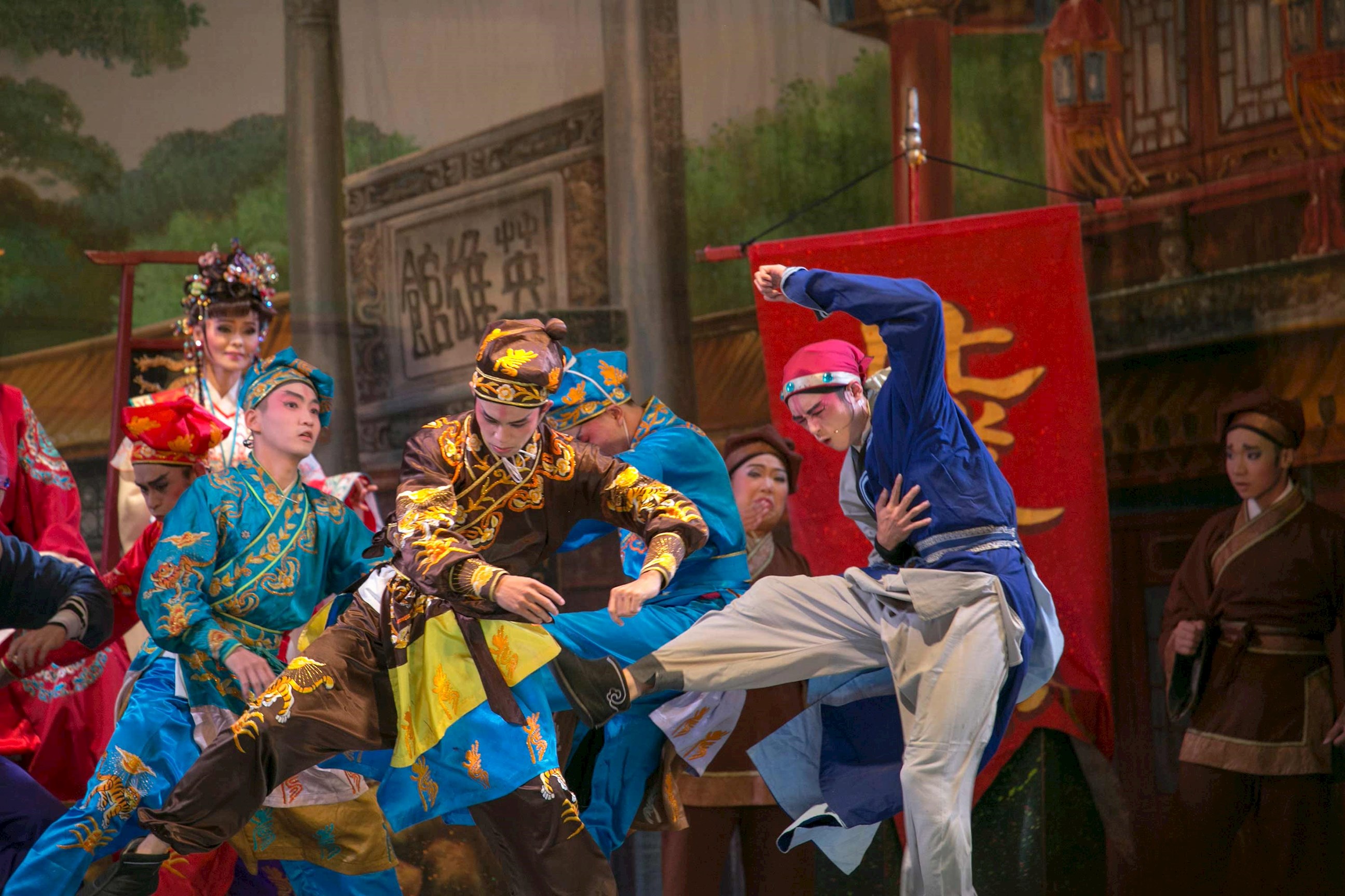 Opera performers in colourful costumes during dramatic stage fight