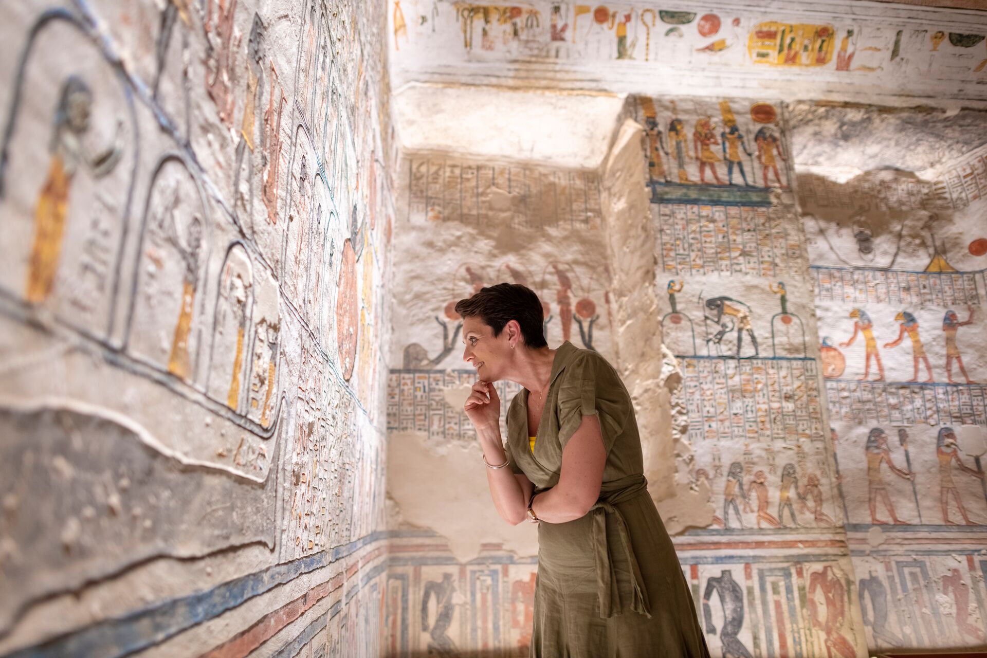 A woman standing in front of a wall with paintings of Ramesses VI Tomb in Luxor, Egypt