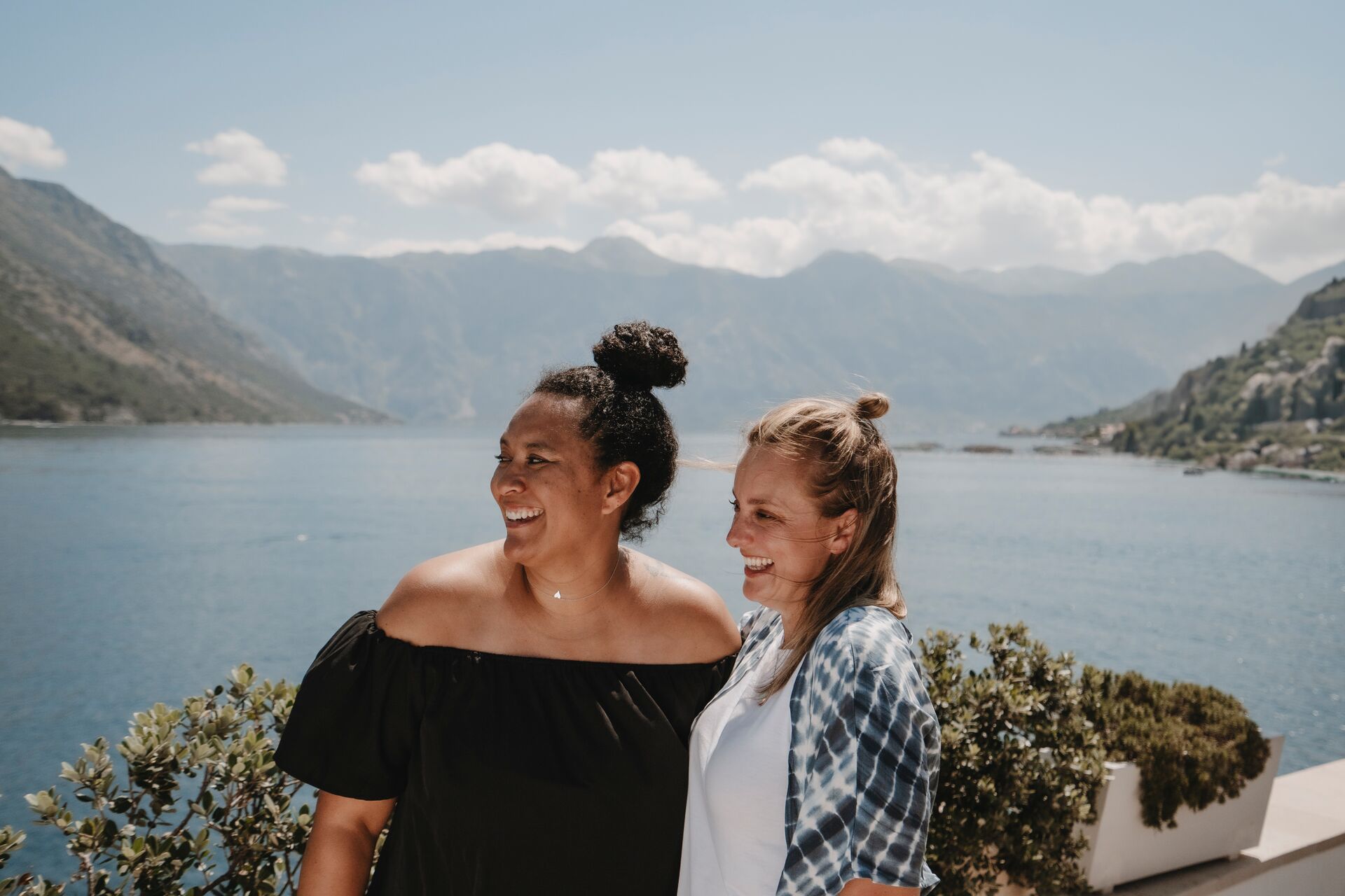 Two women pose in front of a lake