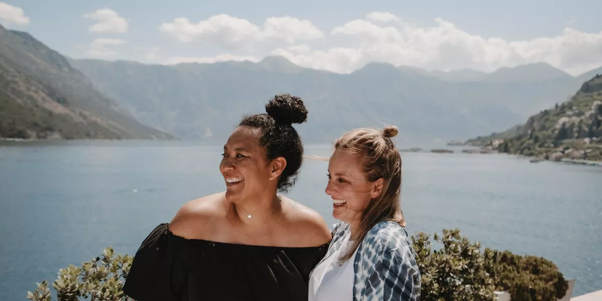 Two women pose in front of a lake