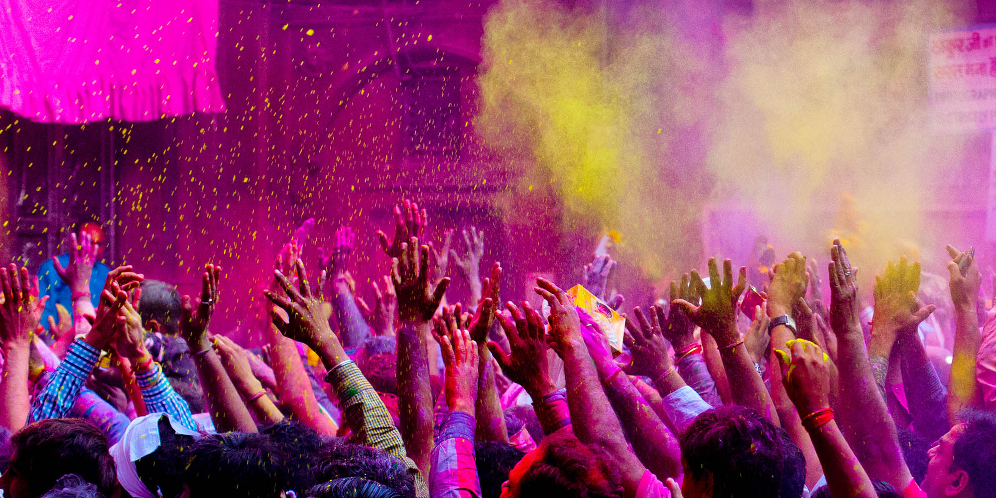 Mass of people covered in powder paint raising hands at Holi festival in India
