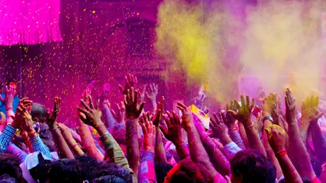 Mass of people covered in powder paint raising hands at Holi festival in India