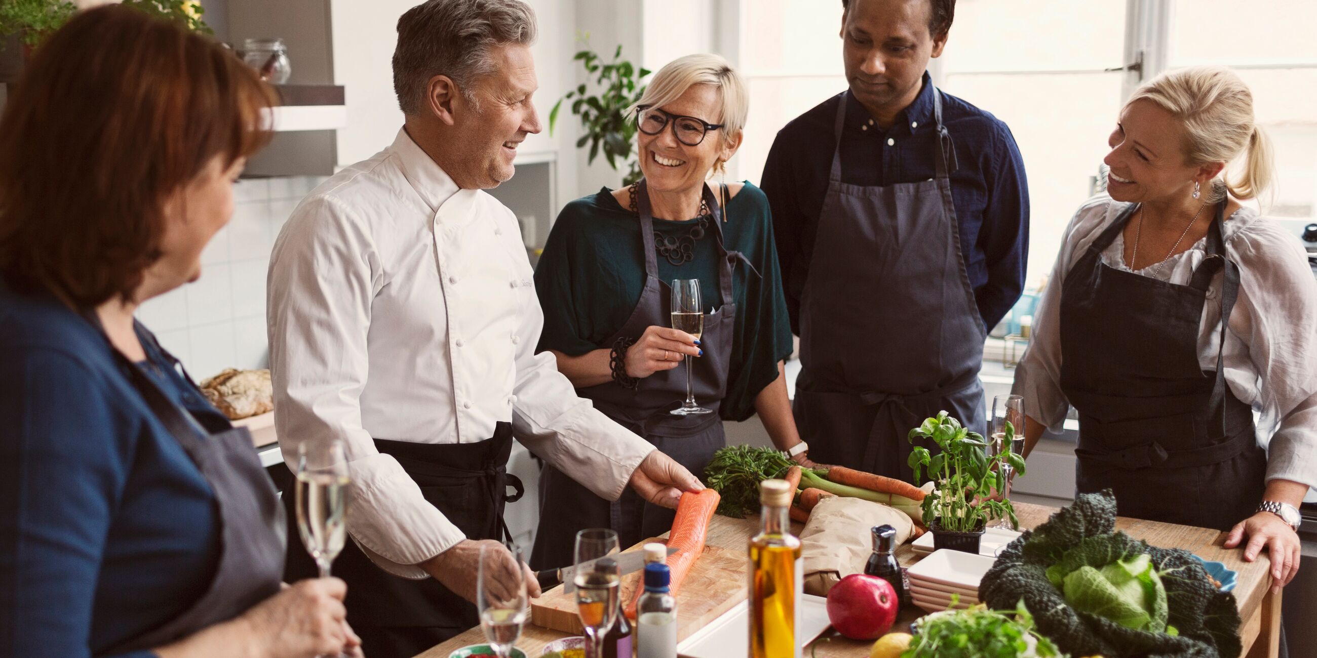 Happy Chef Preparing Food While Teaching To Students Standing At Table