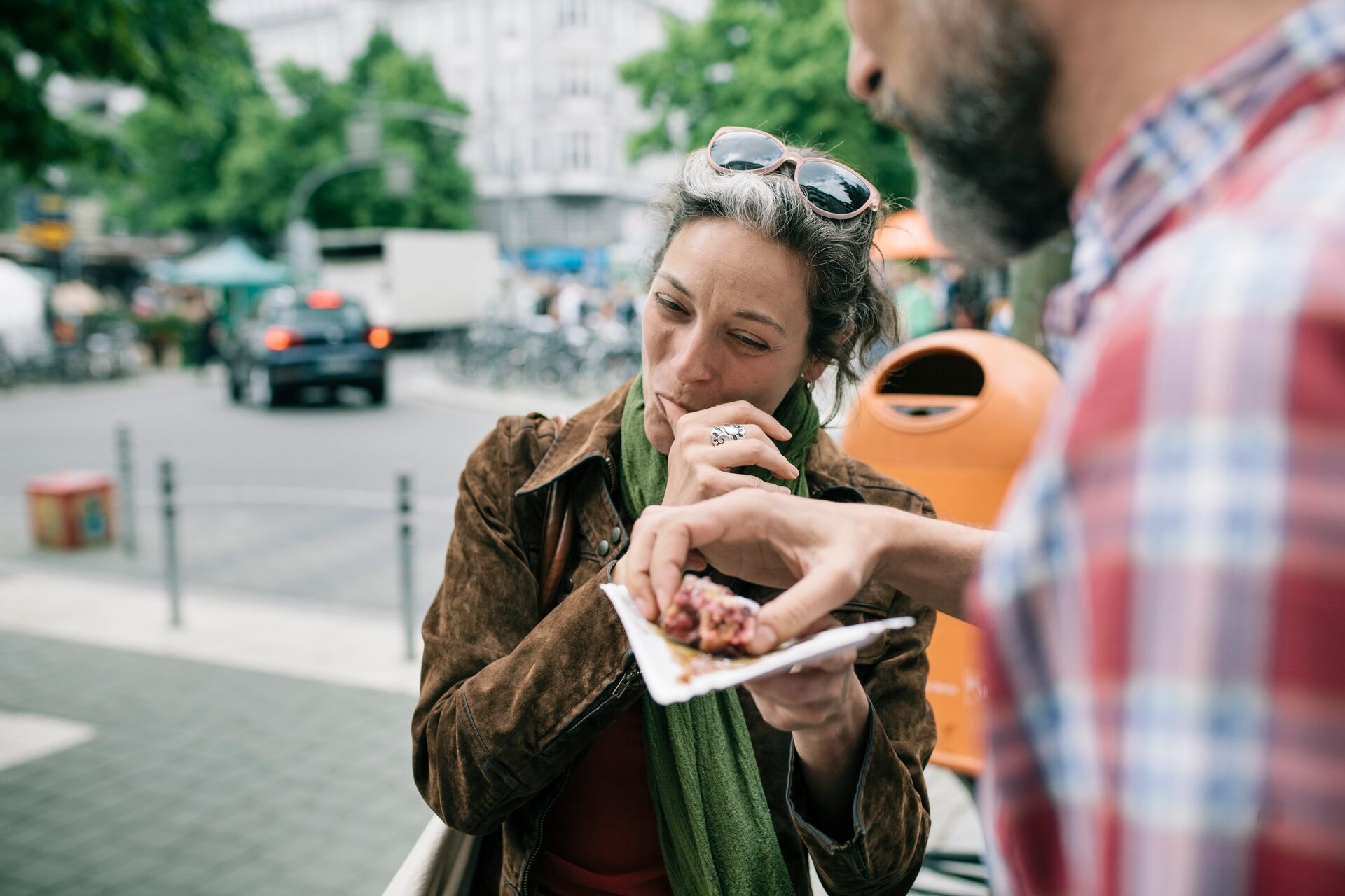 A woman tasting street food outdoors.
