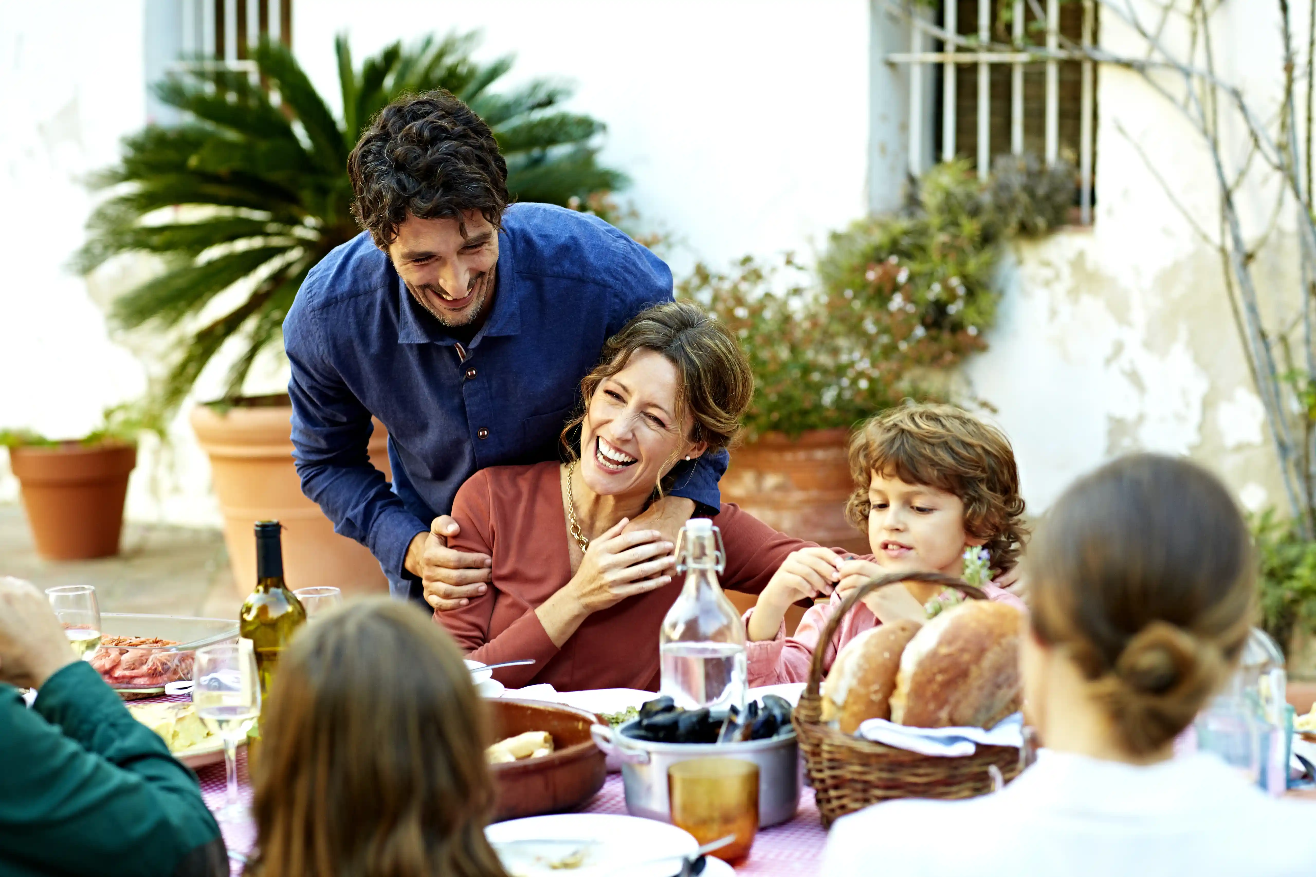 Family Enjoying A Meal At Outdoor Table In A Courtyard