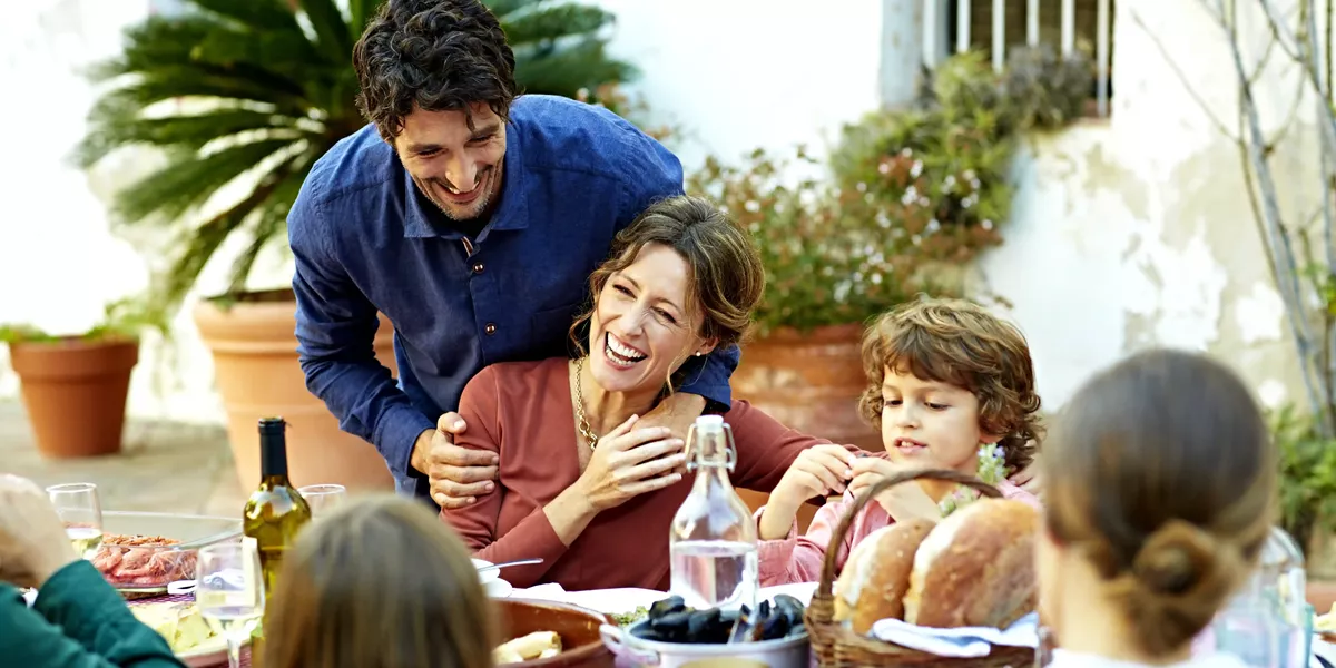 Family Enjoying A Meal At Outdoor Table In A Courtyard