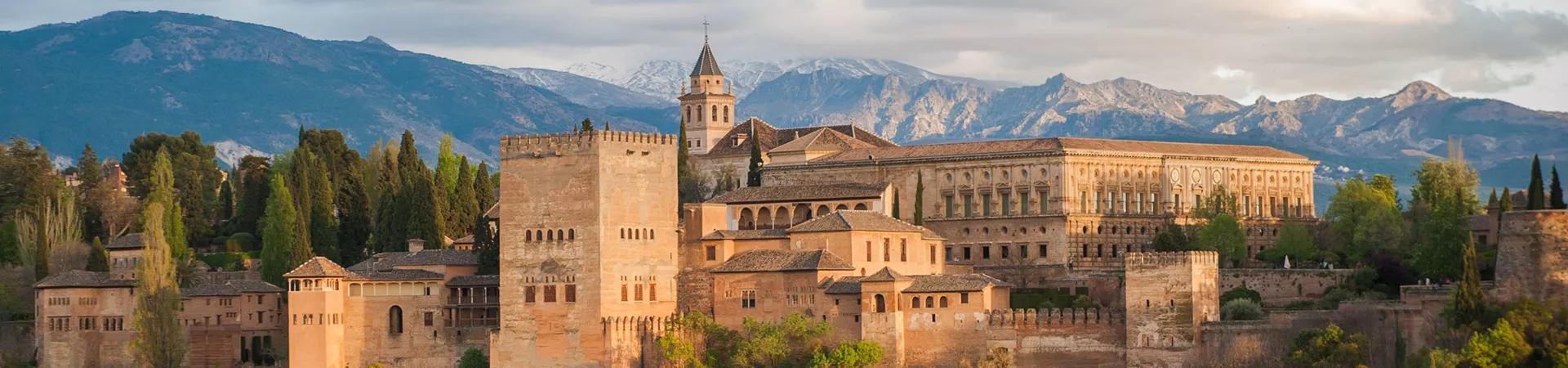 The Alhambra palace in Grenada, Spain. A complex of stone buildings arranged on an imposing plateau.