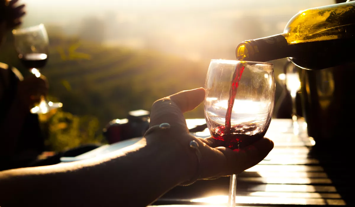 A person pouring red wine into a wine glass