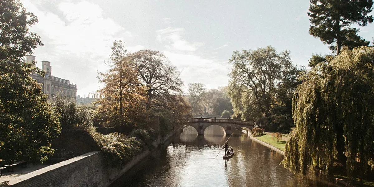 A boat traveling down Cam River in Cambridge, England