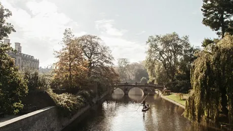 A boat traveling down Cam River in Cambridge, England