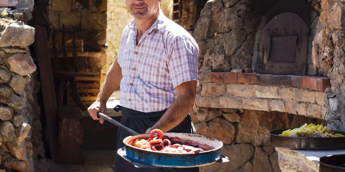 A man holding a frying pan full of food