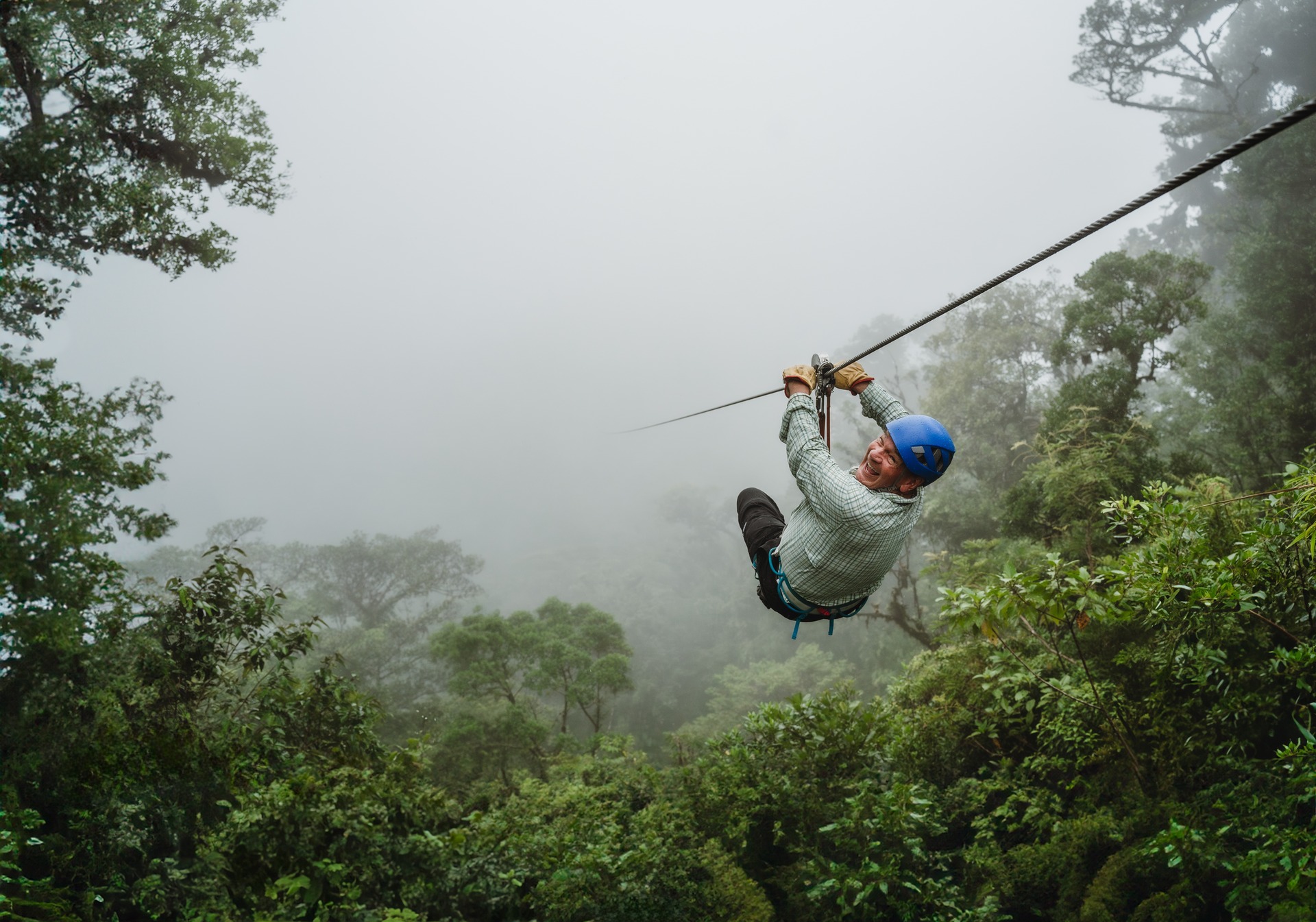 Man wearing a helmet ziplining on a foggy day