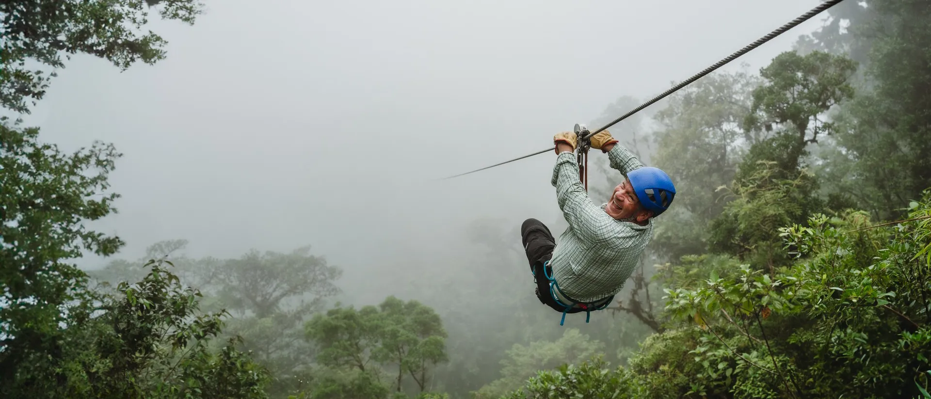 Man wearing a helmet ziplining on a foggy day