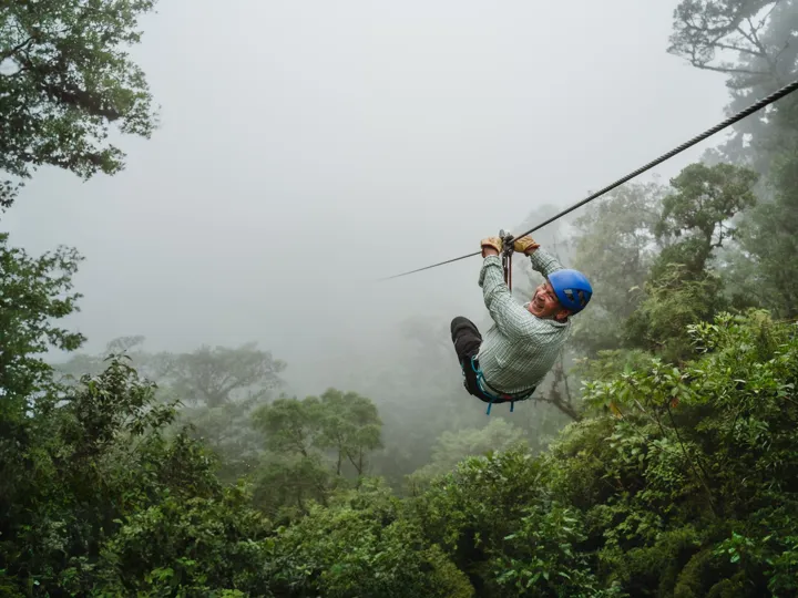 Man wearing a helmet ziplining on a foggy day