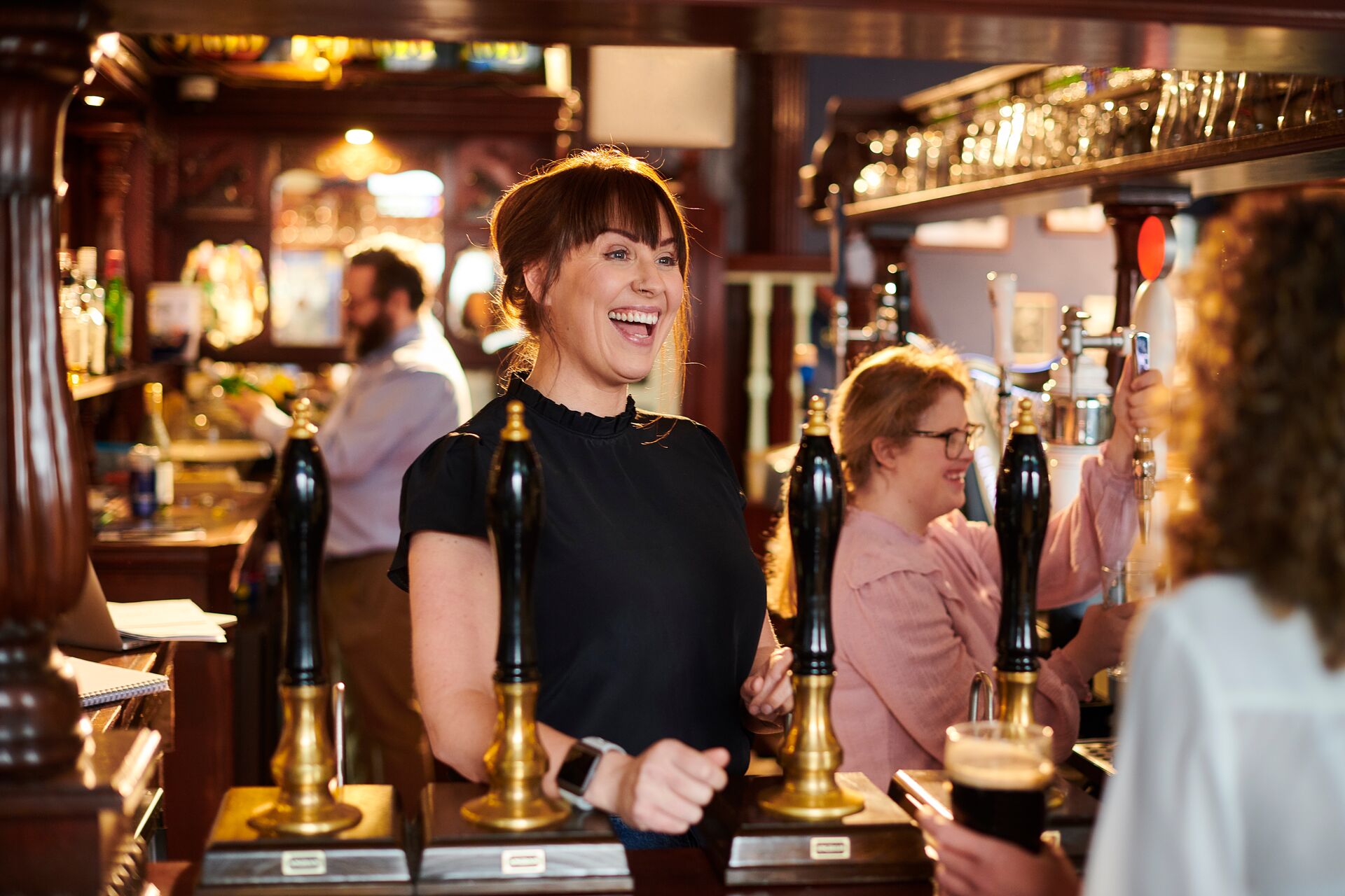 Female bar tender welcoming guests in a traditional pub