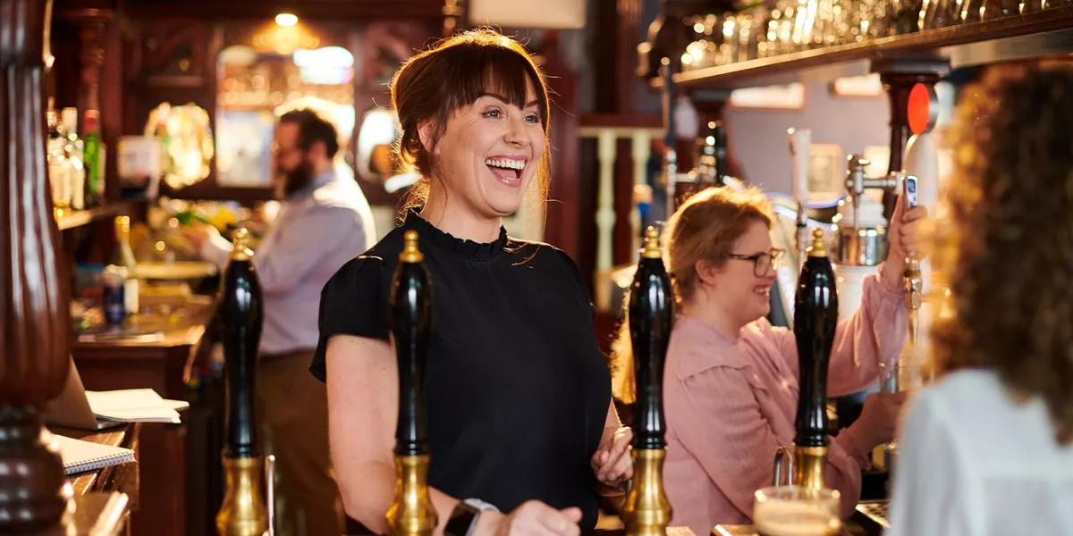 Female bar tender welcoming guests in a traditional pub