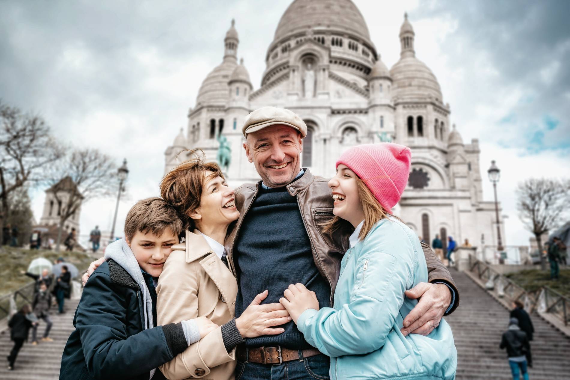 Happy French family embracing in front of Sacre Coeur, Paris, France