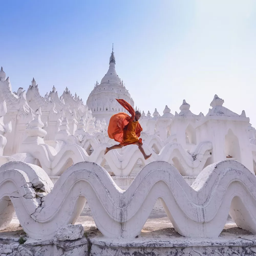 Novice monk jumping on traditional temple in Myanmar