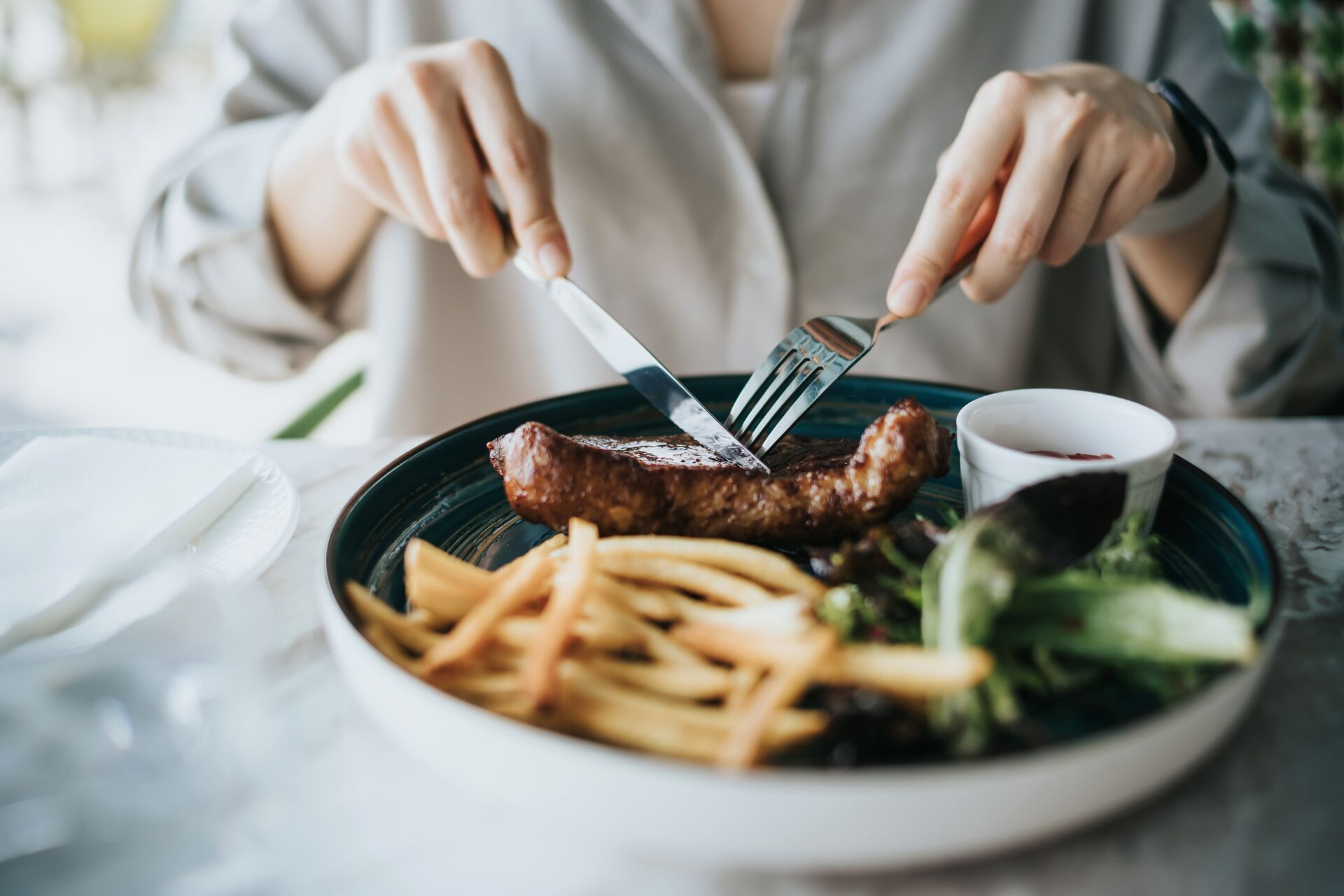 Large Close Up Of Young Woman Cutting A Juicy, Grilled Fillet Steak On Her Plate On Dining Table, Enjoying Lunch In An Outdoor Restaurant Outdoor Dining Lif 1357719354