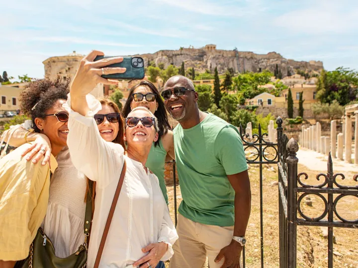 Group of tourists taking selfie in front of ancient ruins in Athens, Greece