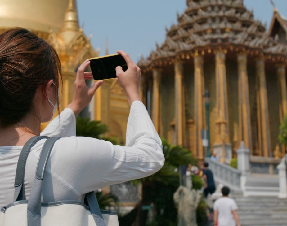 Woman photographing palace in Thailand