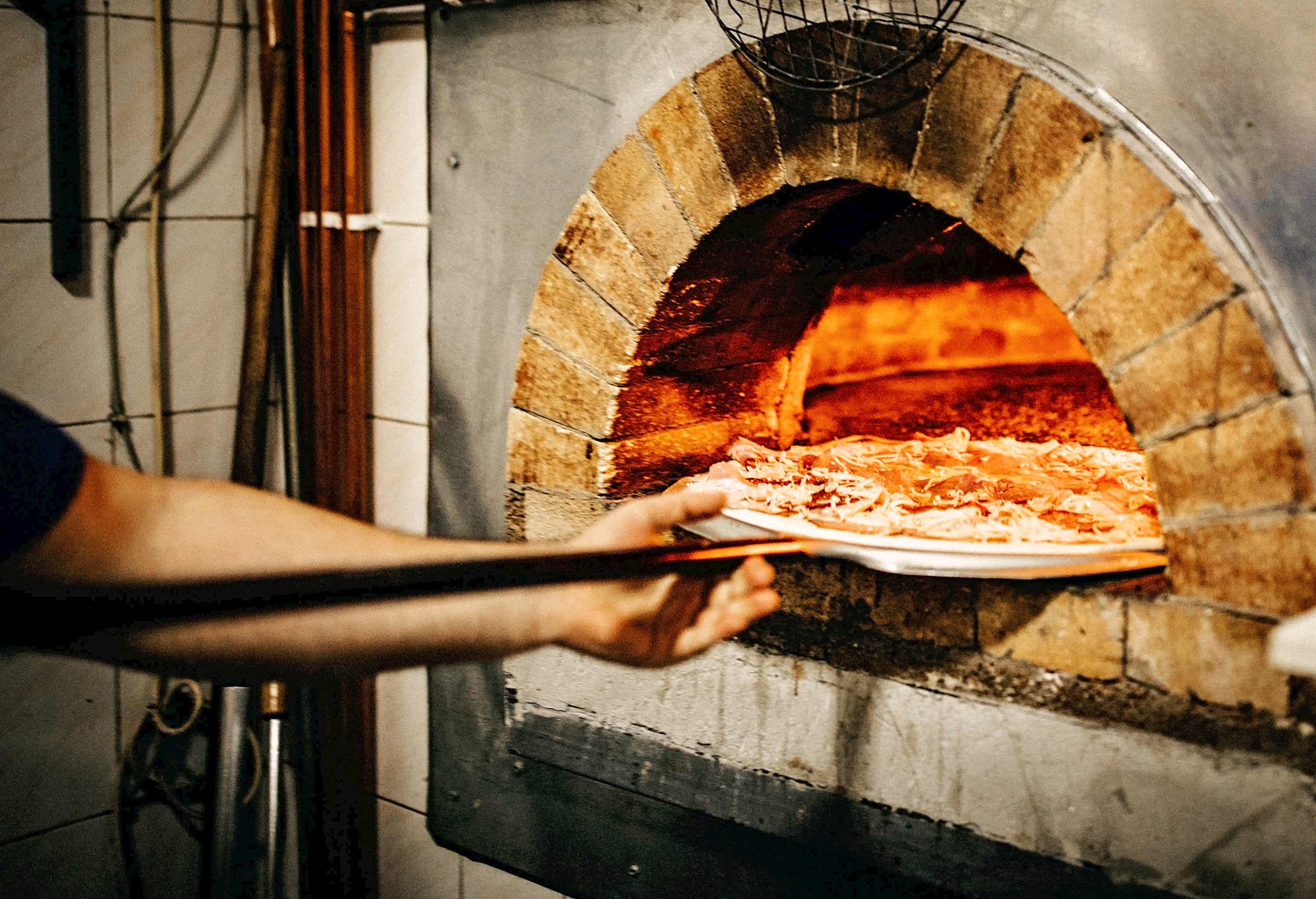 A pizza being put into a woodfire oven