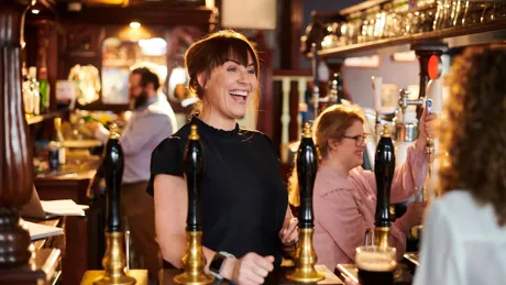 Smiling bartender serving drinks in a traditional pub