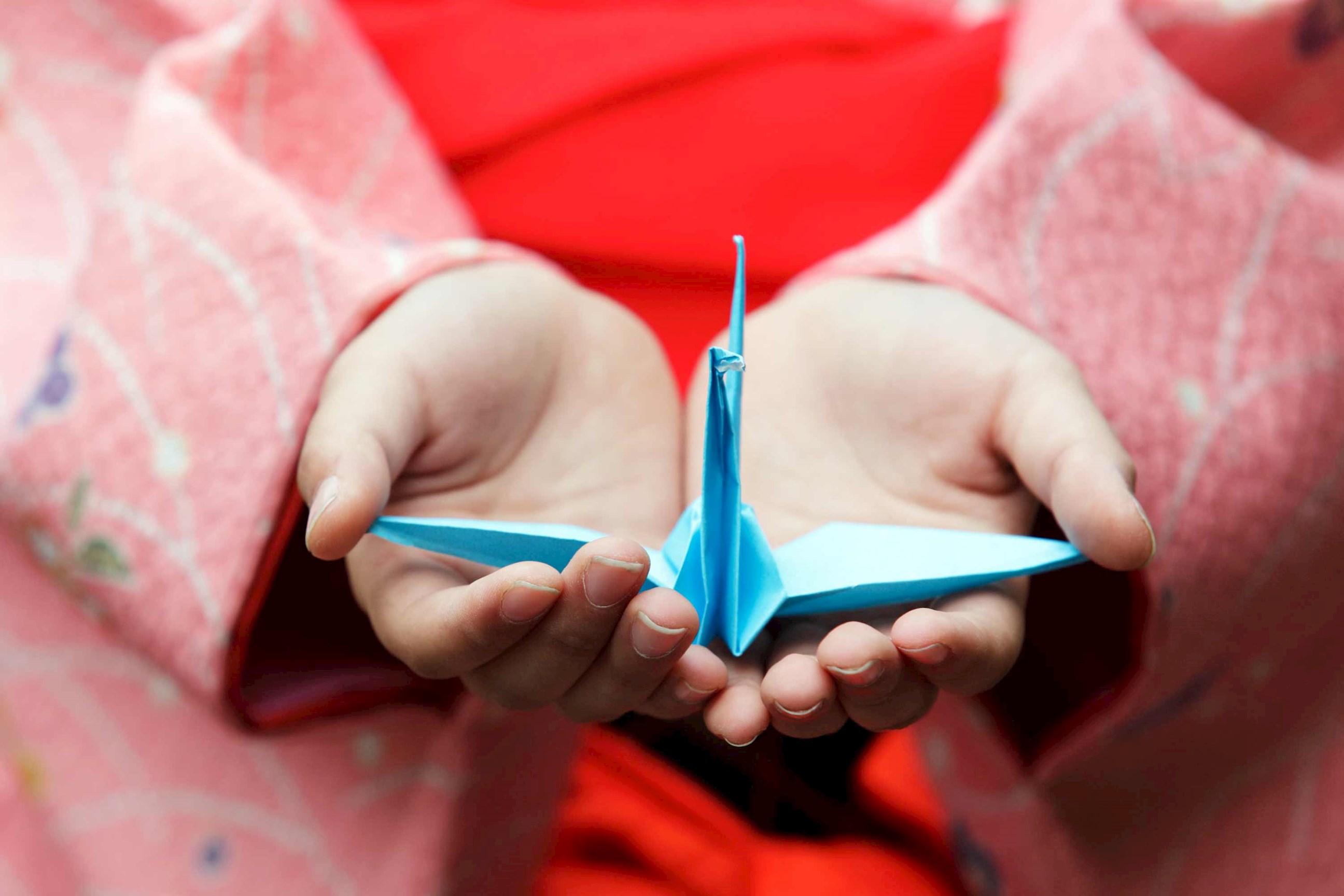 A person holding an origami crane in Hiroshima, Japan
