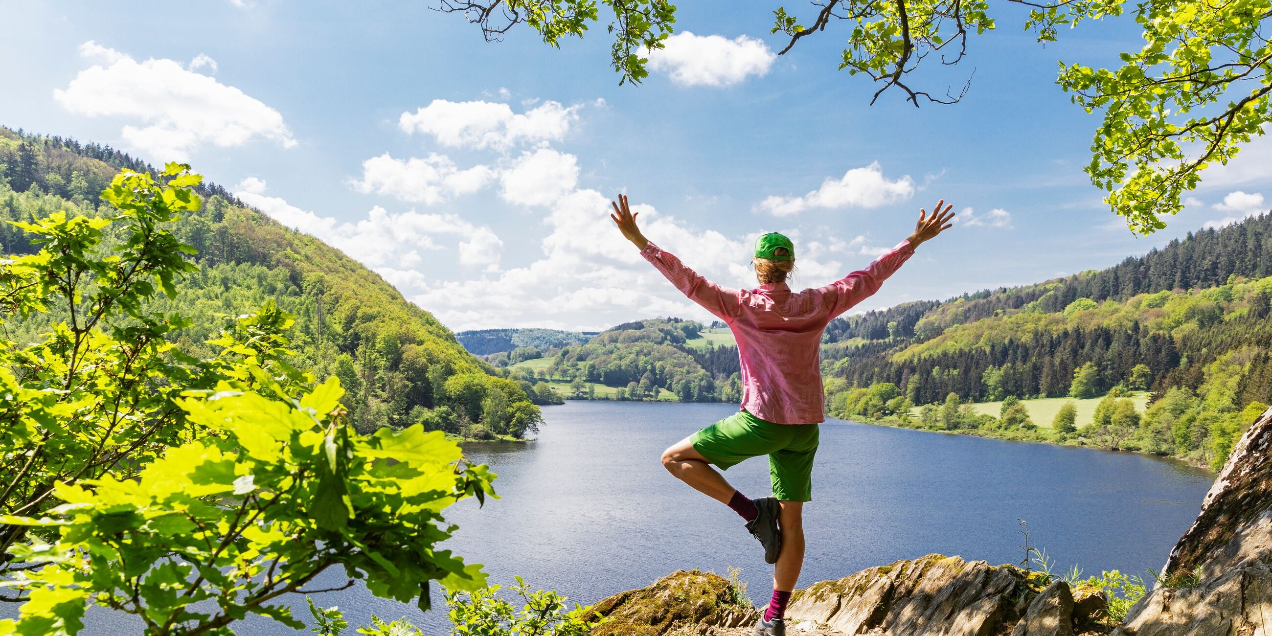 Person standing on a rock ledge overlooking a scenic lake