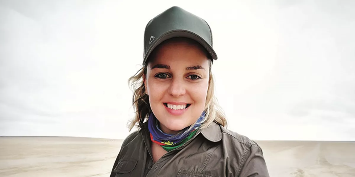 Travel Director Lana Joubert in front of sandy landscape