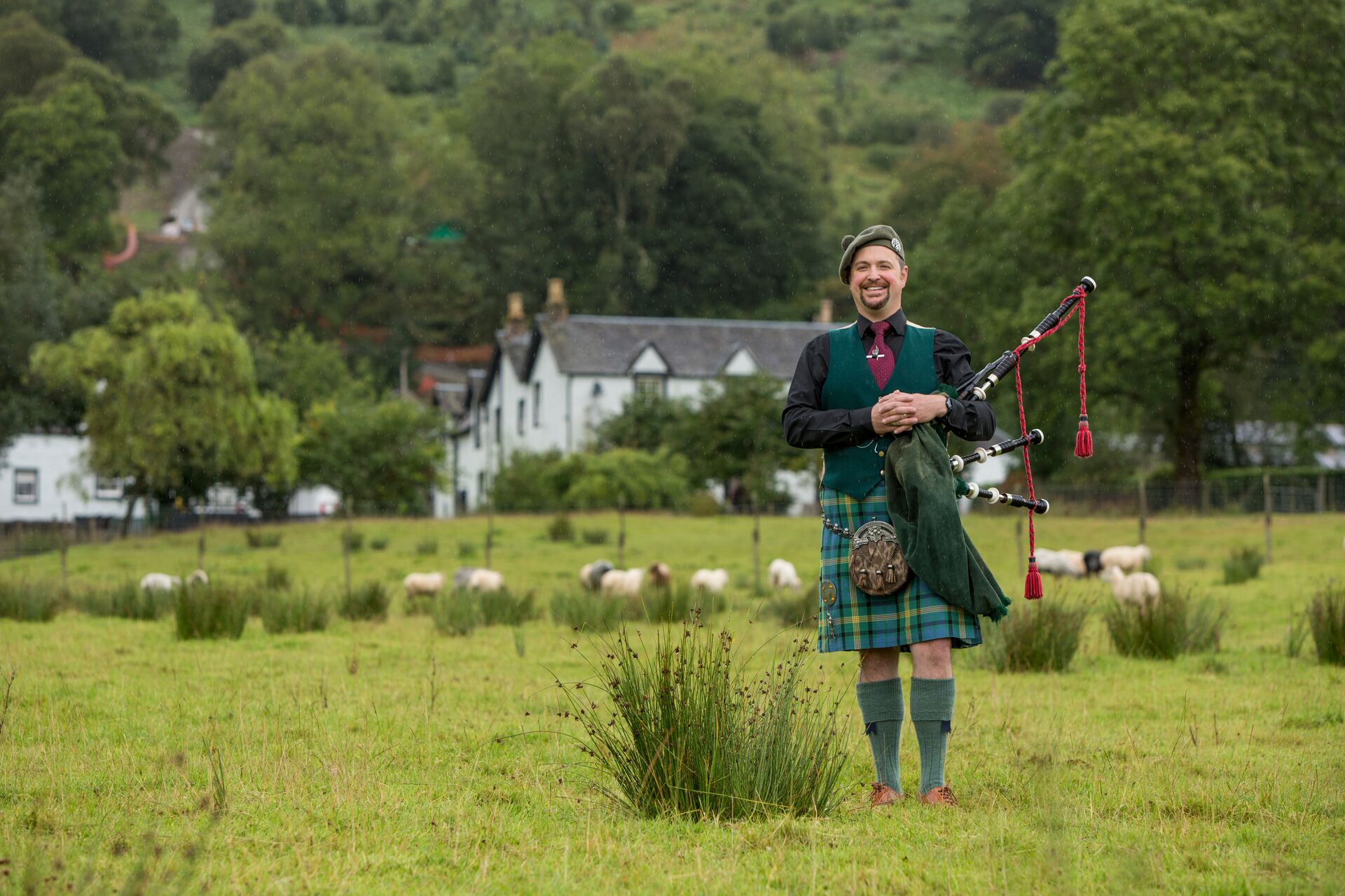 Man playing pipes in traditional Scottish suit on Ledard Farm in Scotland