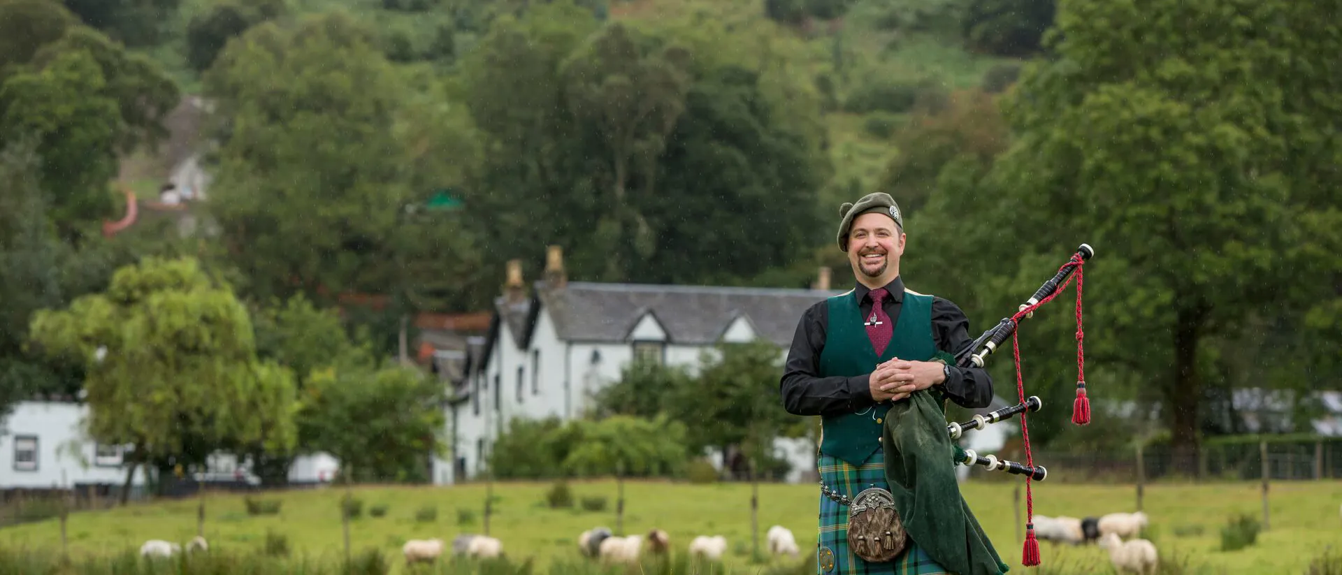 Man playing pipes in traditional Scottish suit on Ledard Farm in Scotland