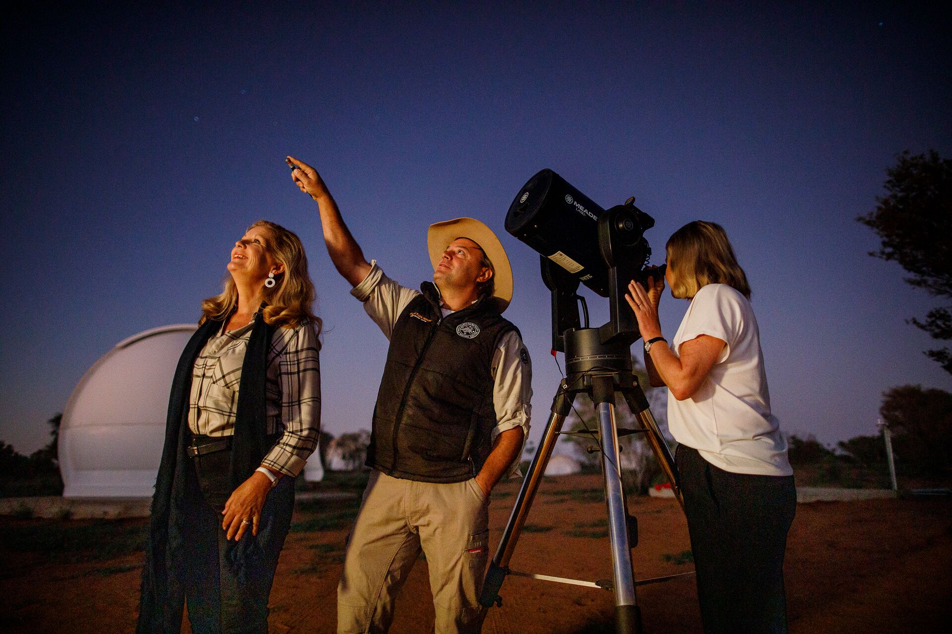 Guests looking at sky next to telescope with Be My Guest host