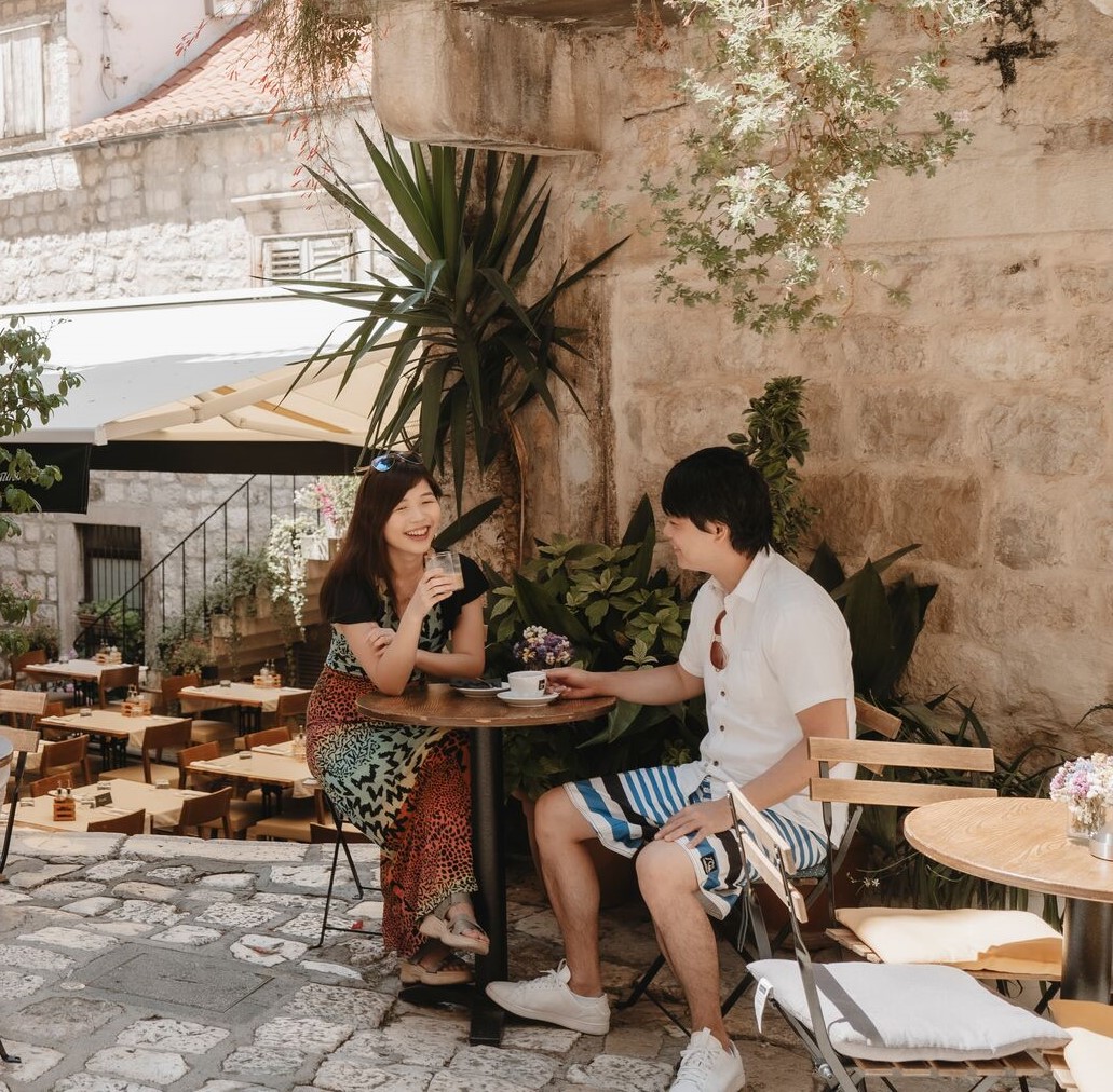 Man And Woman Sitting Outside In Cafe Drinking Coffee