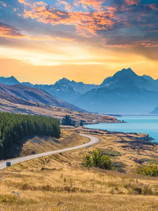 Road in New Zealand with lake and mountains in the background