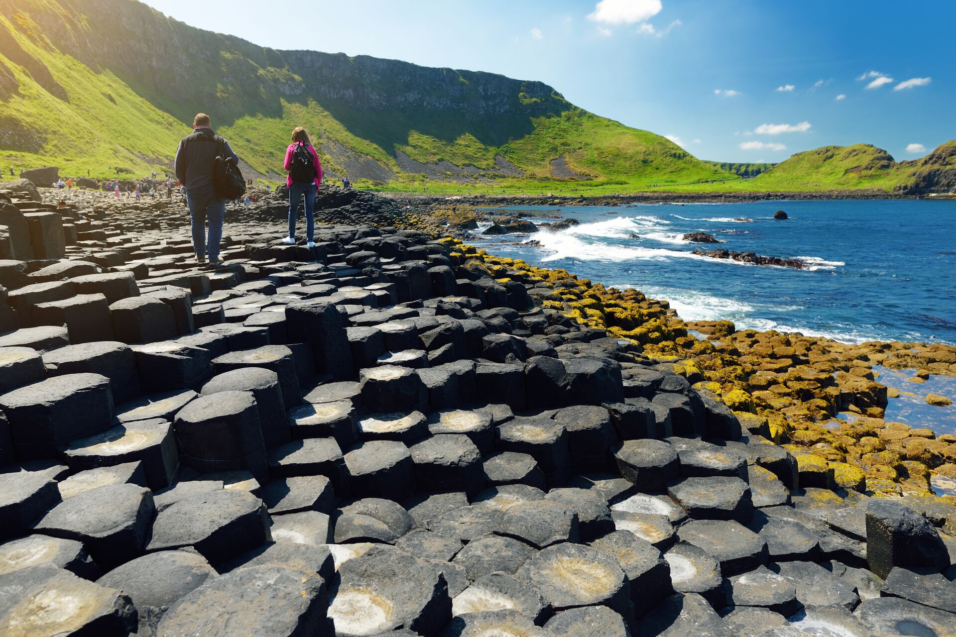 Two tourists walking on the Giants Causeway, a UNESCO World Heritage Site, on a sunny day in Northern Ireland
