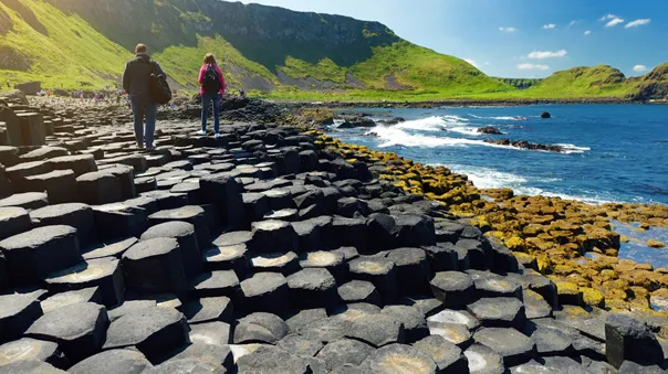 Two tourists walking on the Giants Causeway, a UNESCO World Heritage Site, on a sunny day in Northern Ireland