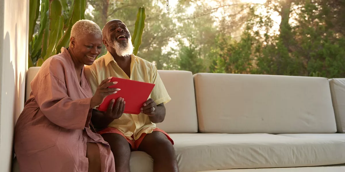 Older couple laugh with a tablet