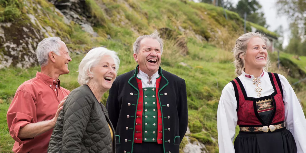 Guests accompanied by hosts wearing traditional clothing on Ovre Eide Farm in Norway