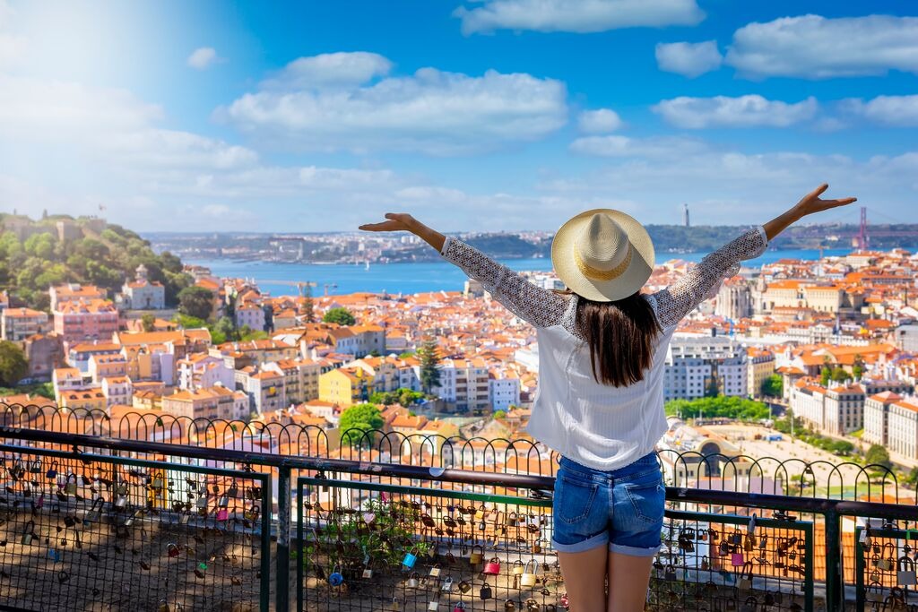 A happy tourist woman overlooks the colorful old town Alfama of Lisbon city 