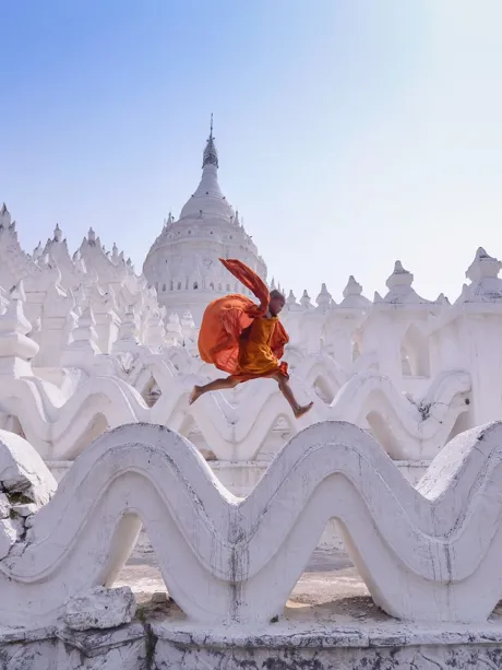Monk jumping on walls of traditional temple in Myanmar