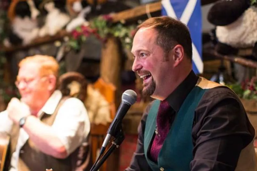 Men Singing with a microphone and a Scottish flag in the background