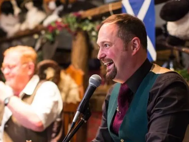 Men Singing with a microphone and a Scottish flag in the background