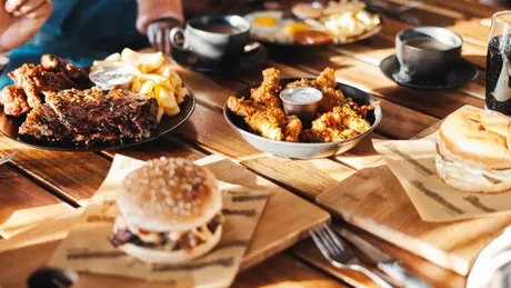 A variety of fast foods such as burgers, chicken wings and ribs laid out on a restaurant table