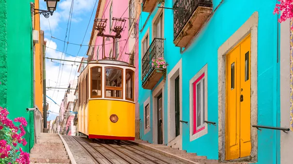 Yellow tram passing colourful houses in Lisbon, Portugal